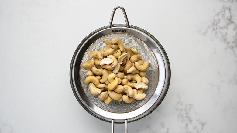 soaked cashews in mesh strainer set over bowl