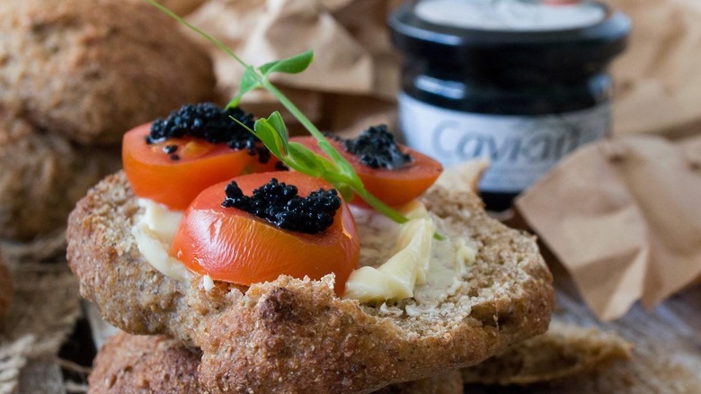 Slice of bread topped with tomato slices and vegan caviar