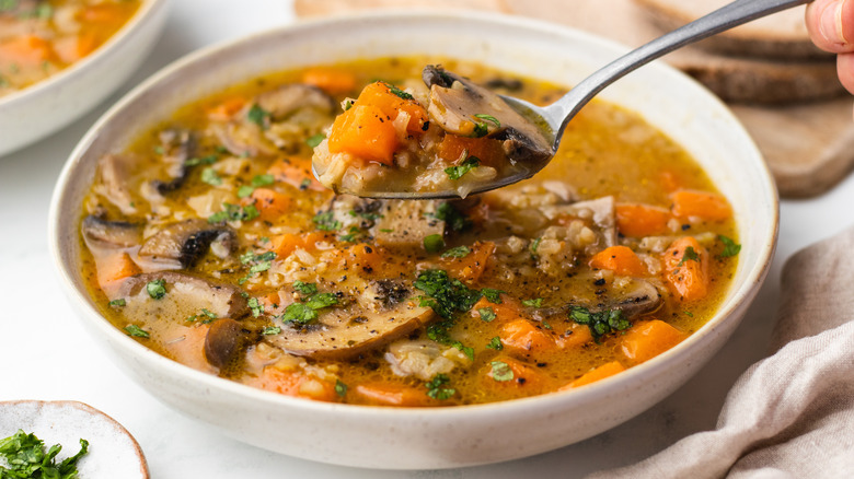 Vegetable soup being spooned out of bowl