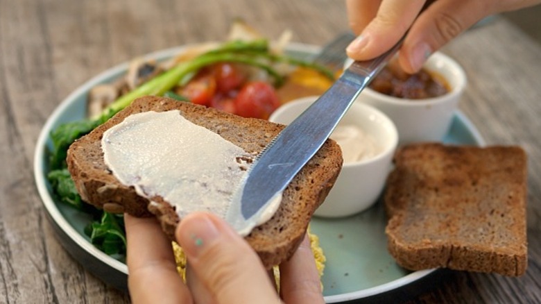 Person buttering wheat toast