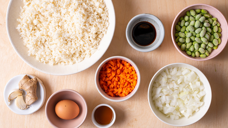 Ingredients gathered on a wooden table to make cauliflower fried rice