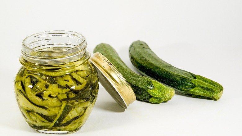 jar of pickled zucchini and whole zucchinis 