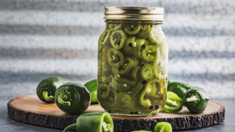 jar of pickled jalapenos on wood board