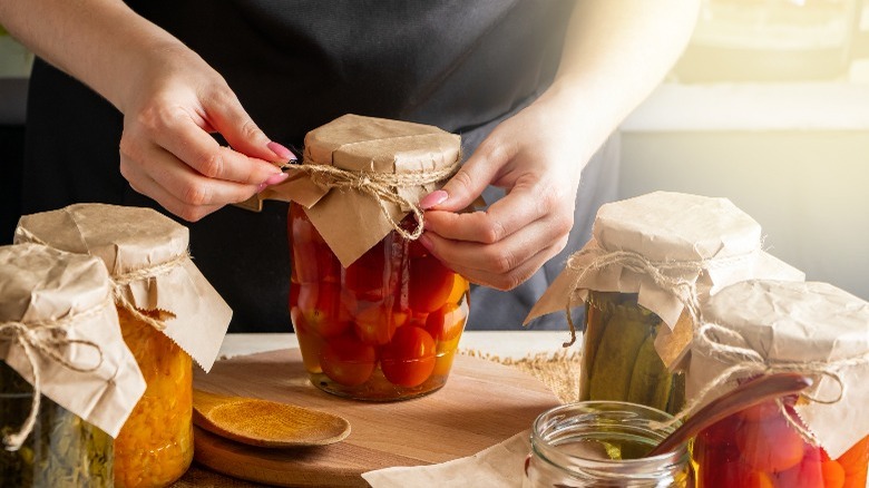 woman tying twine around jar of tomatoes