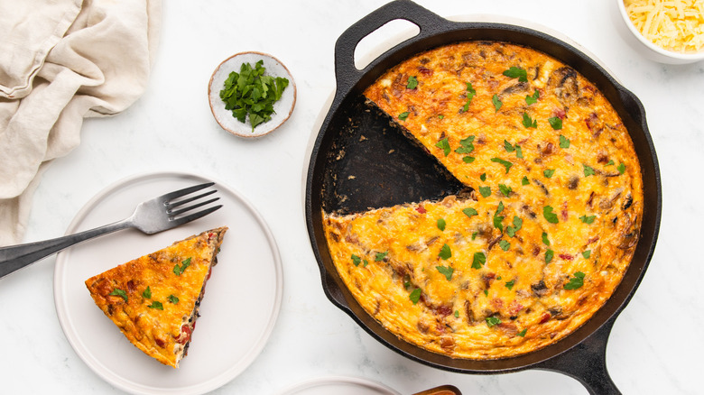 Veggie frittata in skillet with slice on plate