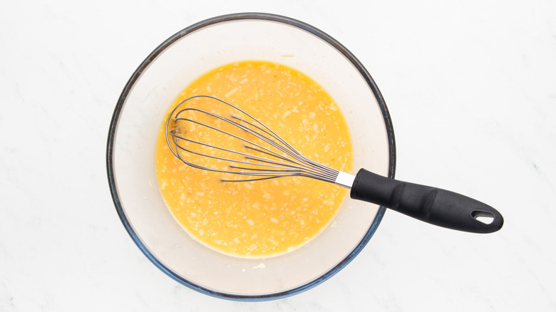 Whisking eggs and shredded cheese in mixing bowl