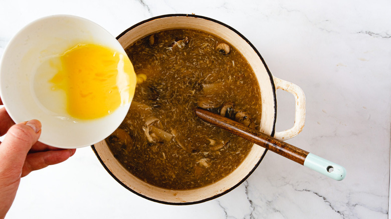 adding whisked egg to soup