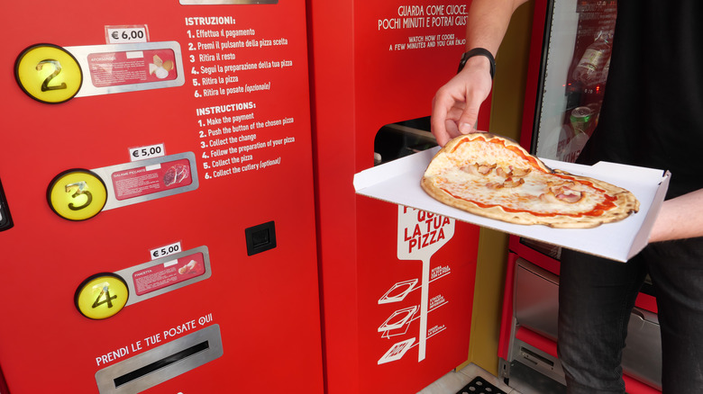 Pizza being taken from vending machine