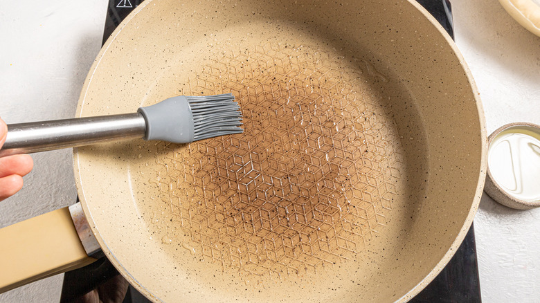 Brushing a skillet with oil using silicon brush