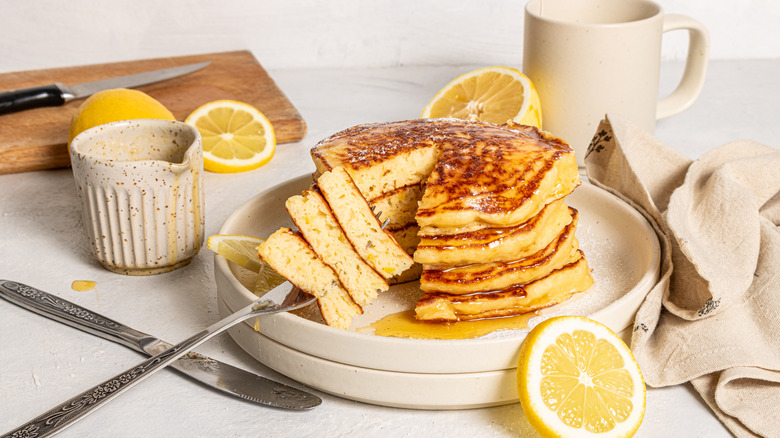 Stack of pancakes on a plate with a fork and pancakes on it