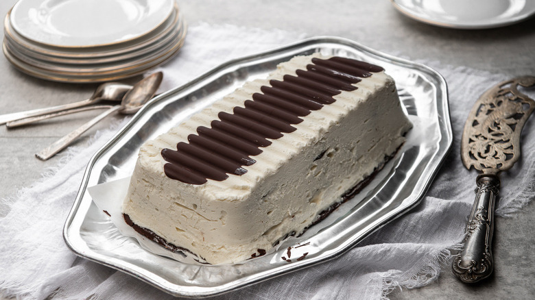 viennetta cake on a silver platter with a serving spatula and plates on a white counter