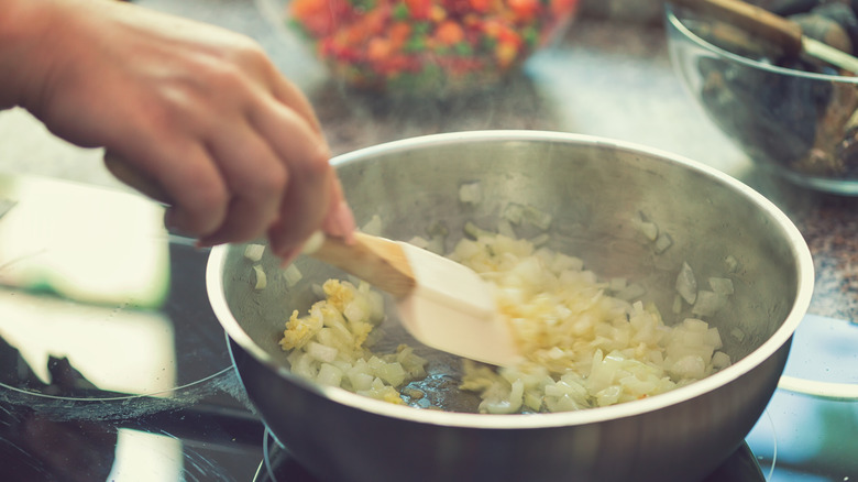 hand sauteing onions in a pan