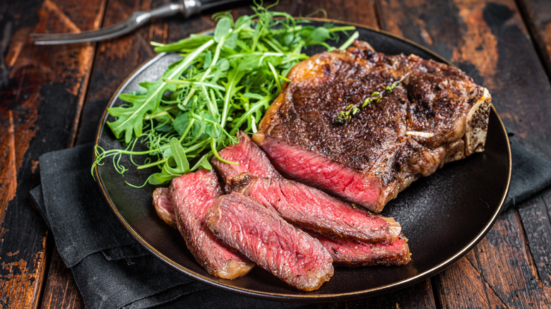 Sliced wagyu streak with greens on black plate