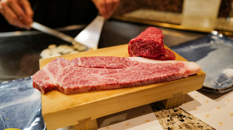 Well-marbled Kobe beef on wooden cutting board