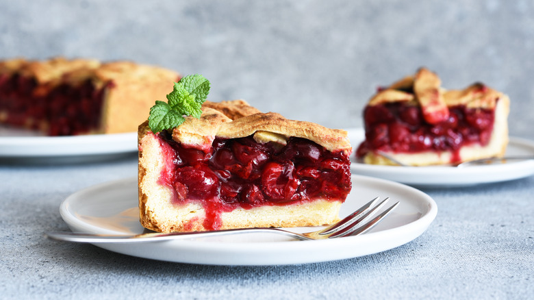 A slice of cherry pie on a plate with a fork