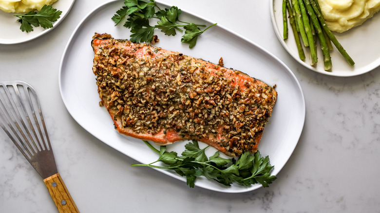 cooked salmon with parsley garnish on white plate