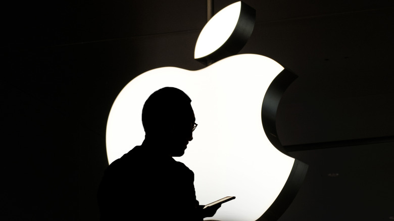 Silhouette of person in front of neon Apple logo