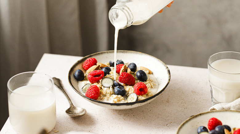 Milk poured into a bowl of oatmeal with berries