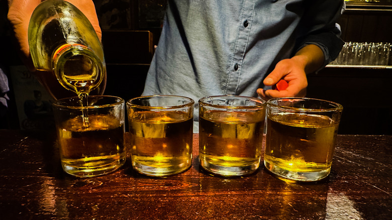 bartender pouring whiskey into glasses