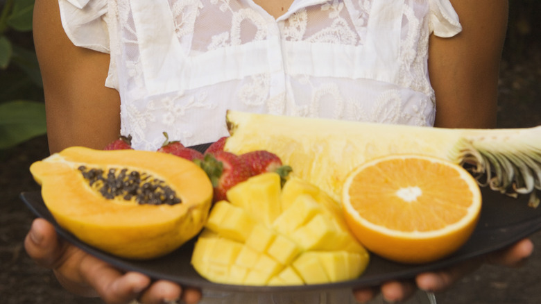 hands holding tropical fruit tray