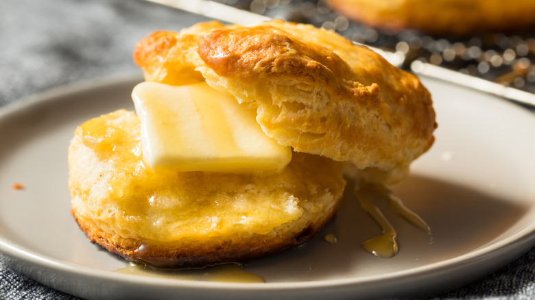 A hot biscuit with butter and honey on a plate