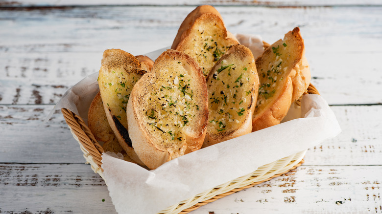 Garlic bread in a basket on a white table