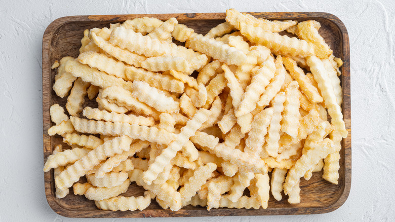 frozen crinkle cut fries on wooden tray