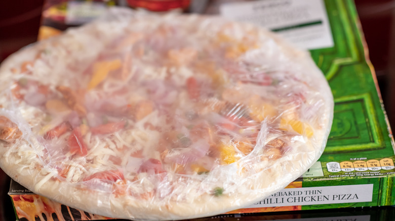 frozen pizza in plastic wrap on top of box