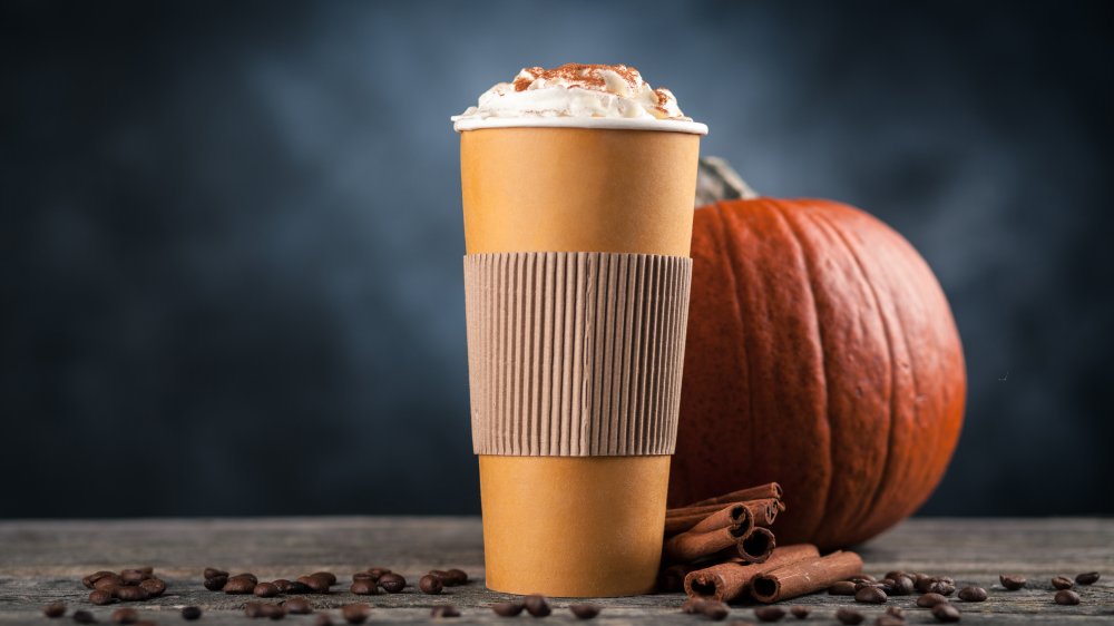 large pumpkin spice latte with a pumpkin behind the to-go cup