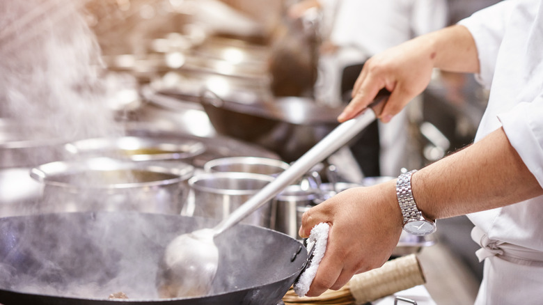 Chef cooking with wok and ladle