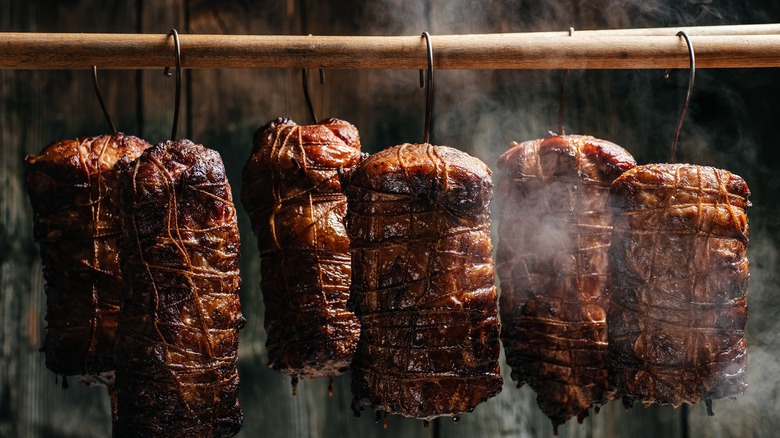 smoked slabs of ham hanging up