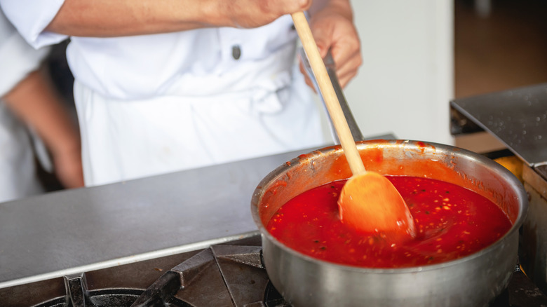 Chef simmering tomato sauce stove