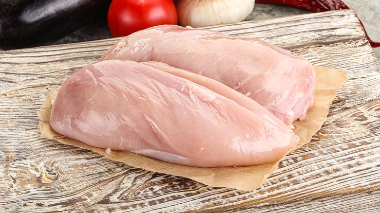 Raw chicken breasts cutting board