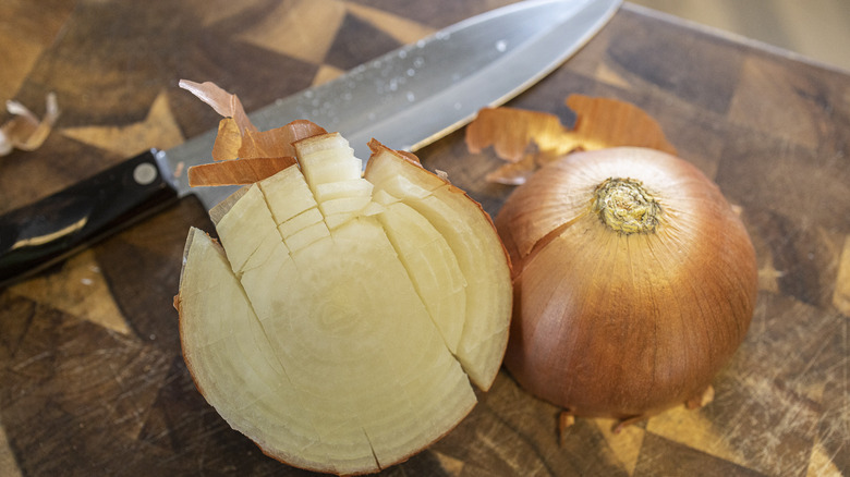 Checkerboard cut onion on cutting board with knife