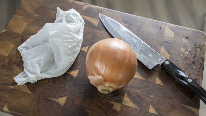 Onion and knife on wooden cutting board