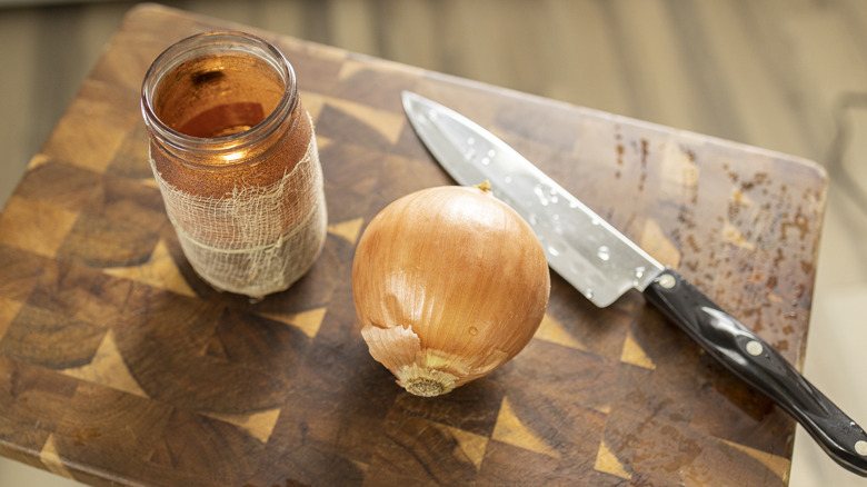 Onion and candle and knife on cutting board