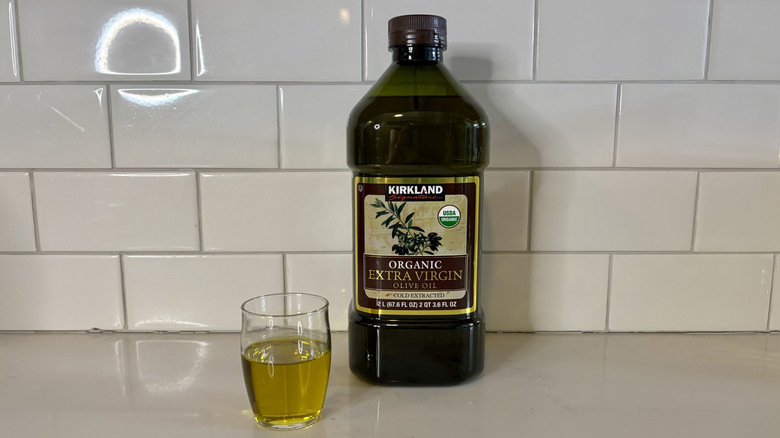 a dark bottle of organic olive oil with glass of olive oil