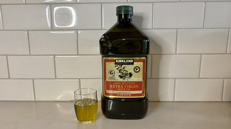 a dark bottle of Spanish olive oil with glass of olive oil