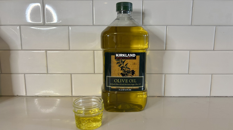 a bottle of yellow Kirkland olive oil with glass container