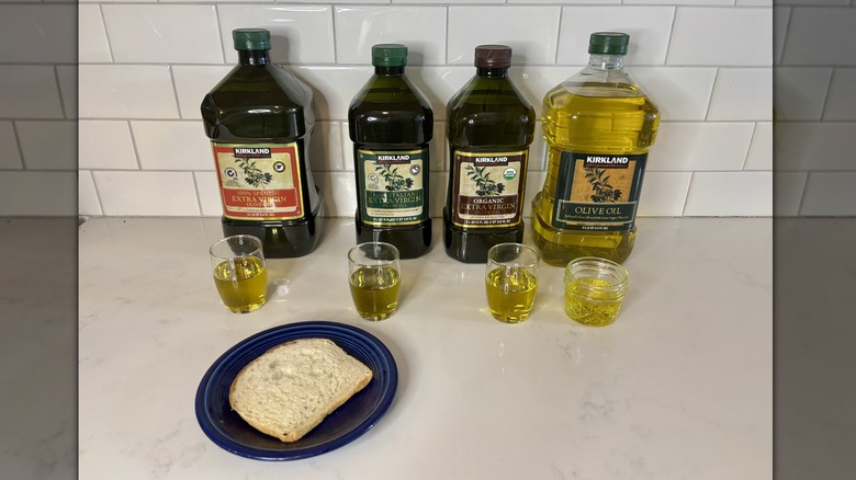 four bottles of olive oil and a piece of bread on blue plate