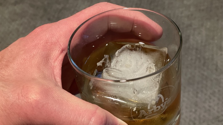 a hand holding a glass of bourbon