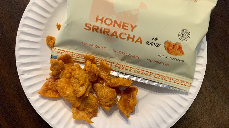 Fried chicken skin chips on a plate next to a bag