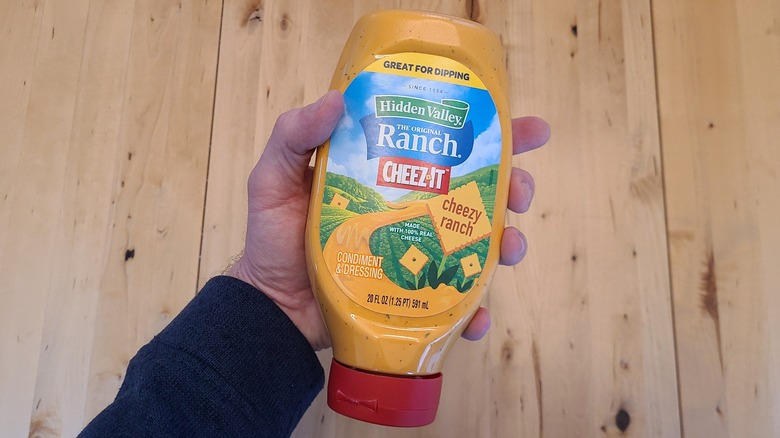 a hand holding a bottle of cheez-it ranch dressing