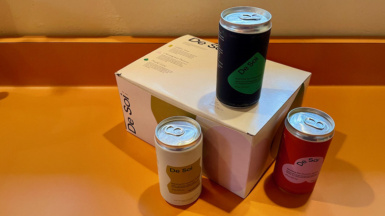 three cans of de soi on white box