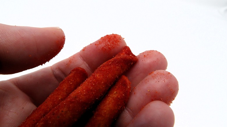 Hand holding red-orange Takis Kaboom chips