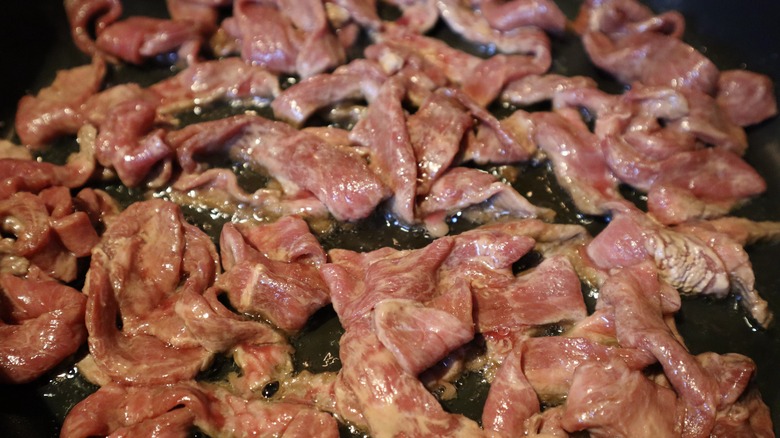 stir fry beef strips cooking in pan