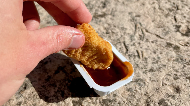 dipping nugget into barbecue sauce