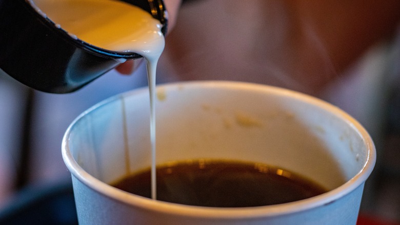 Creamer pouring into cup of coffee