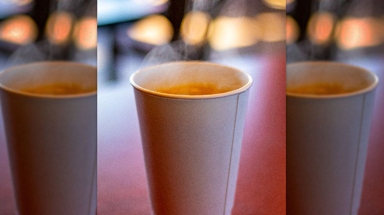 Cup of steaming coffee on table