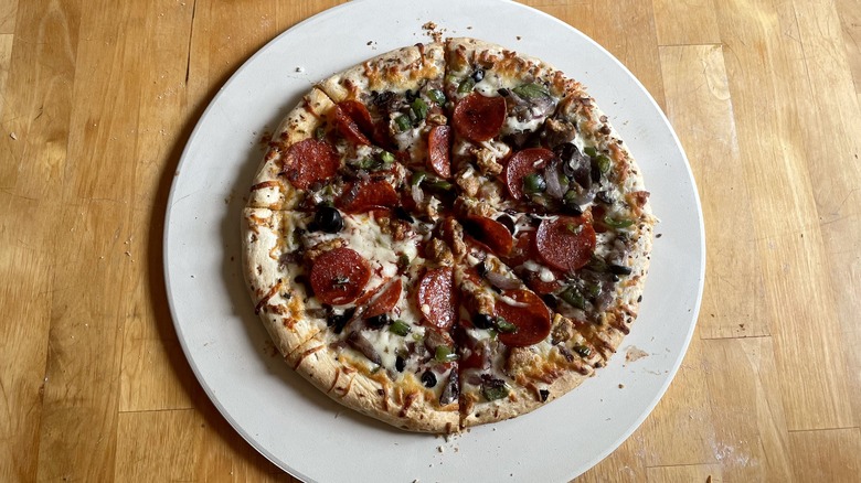 Supreme pizza on pizza stone, cut